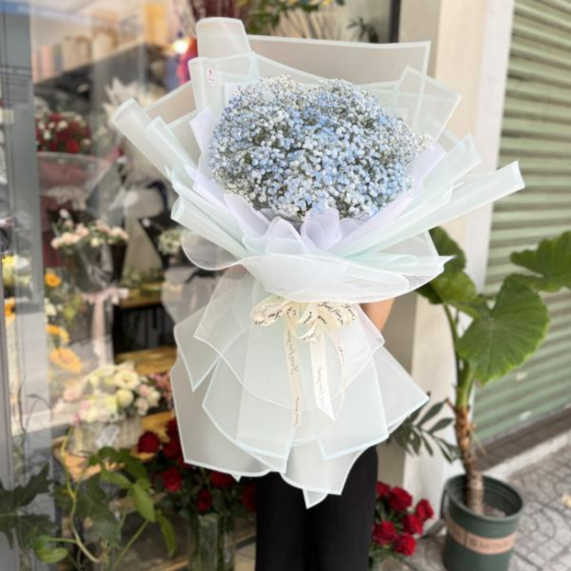 Một người phụ nữ đang chọn những bông hoa tươi với màu sắc nhẹ nhàng tại cửa hàng hoa, thể hiện sự tinh tế khi chọn hoa cho người 17/7 cung gì.